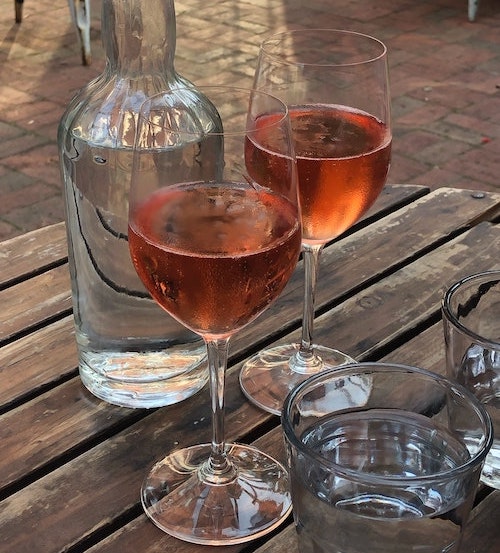 Two glasses of red wine on a wooden table.