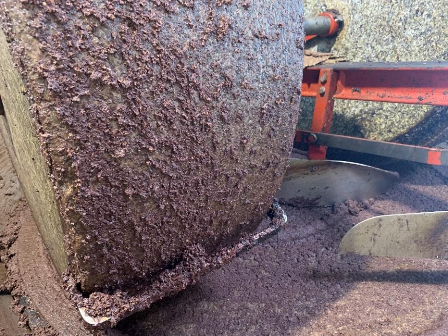 Olives being ground into a paste using a stone wheel.