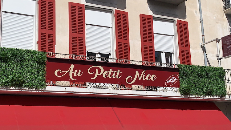 A red sign that says 'Au Petit Nice' in curling script.